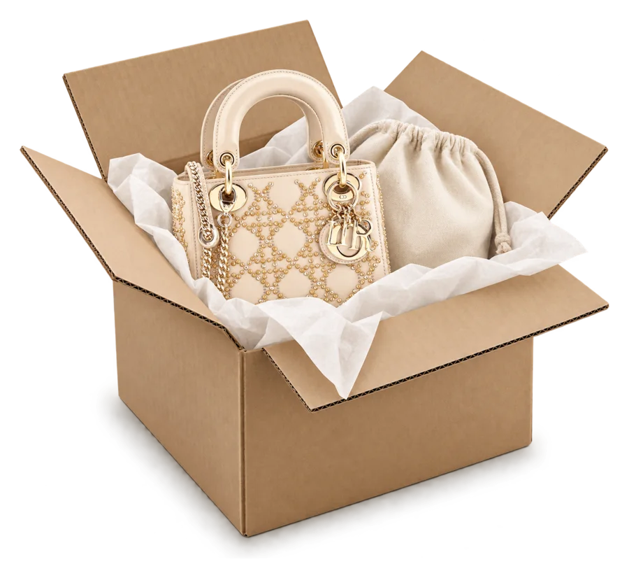 A cream Lady Dior in tissue inside a shipping carton